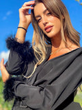 Abito nero con maniche con piume