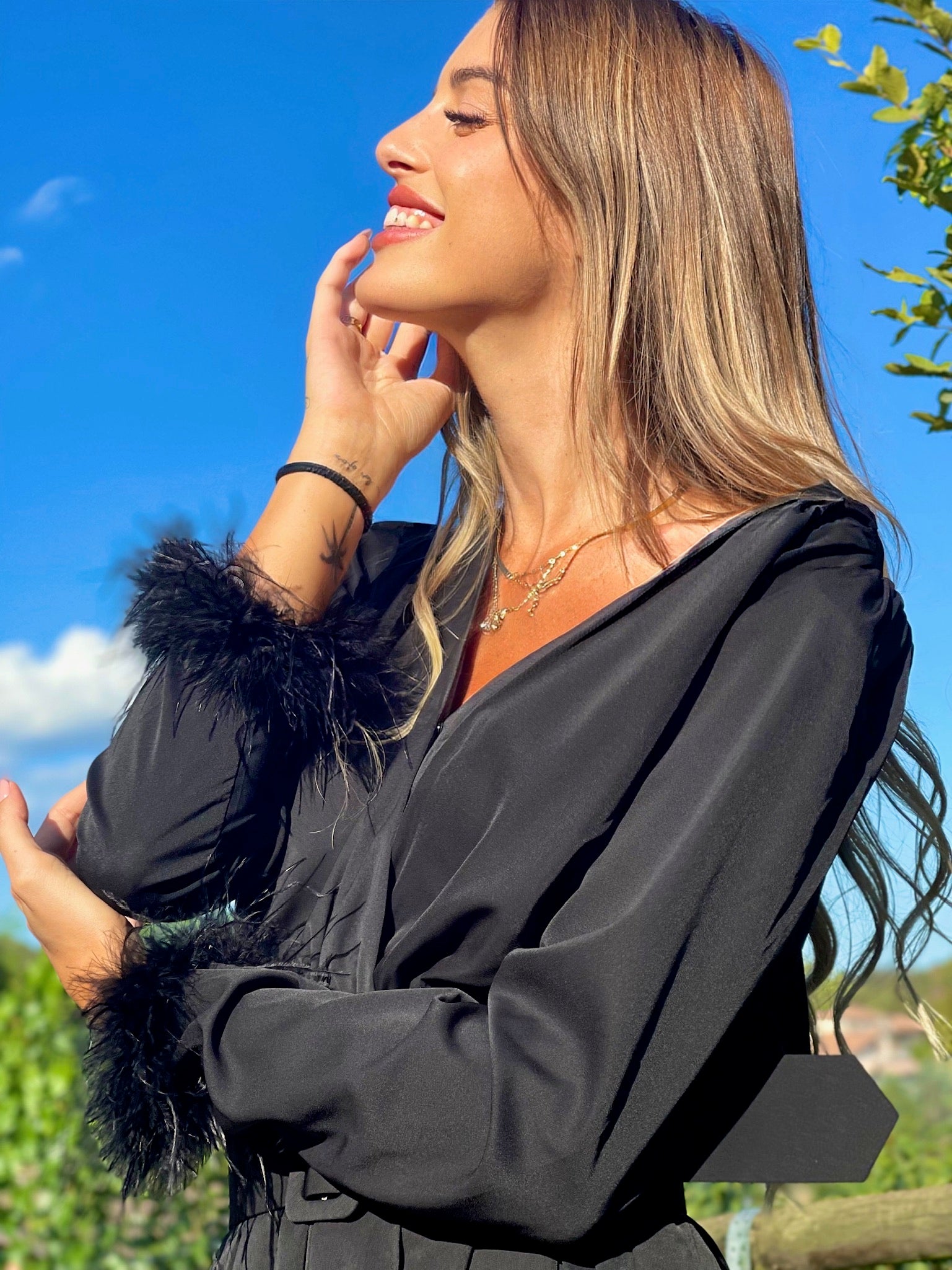 Abito nero con maniche con piume