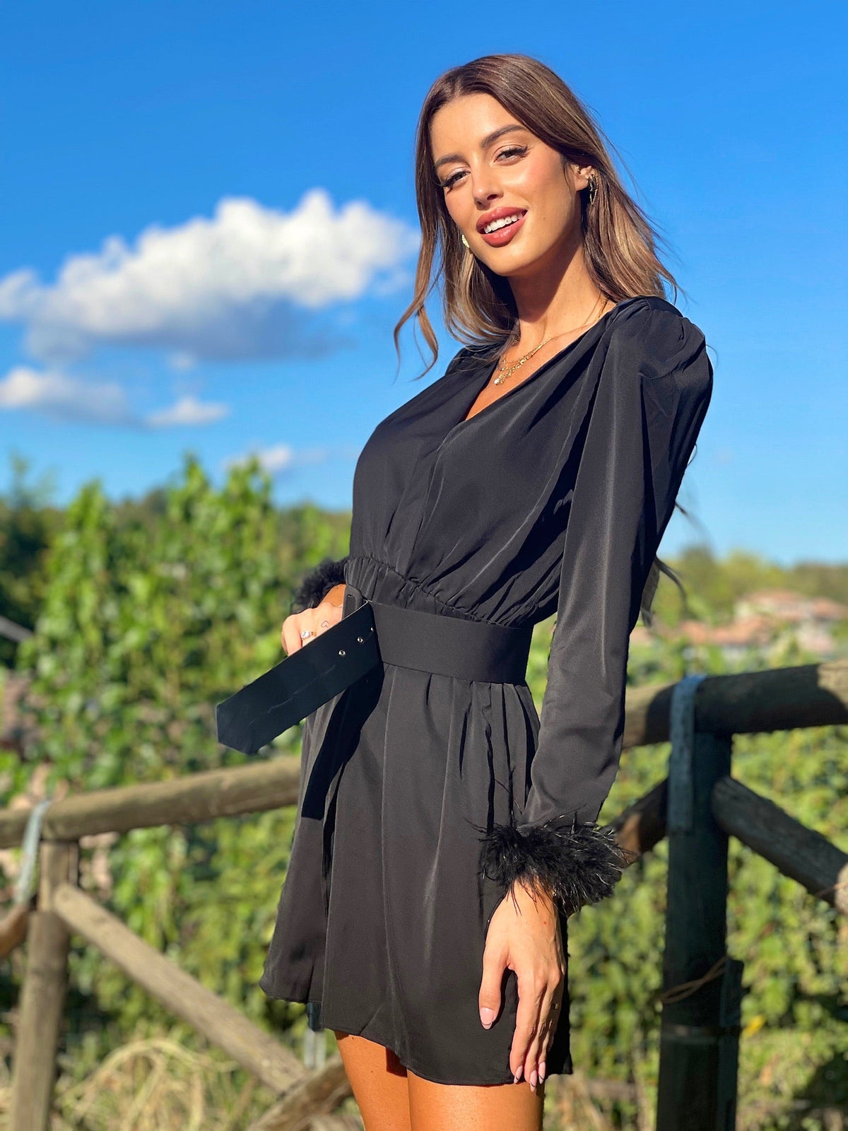 Abito nero con maniche con piume