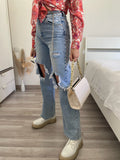 Jeans con strappi e cintura con catene