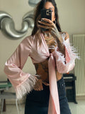 Camicetta con fiocco e piume rosa